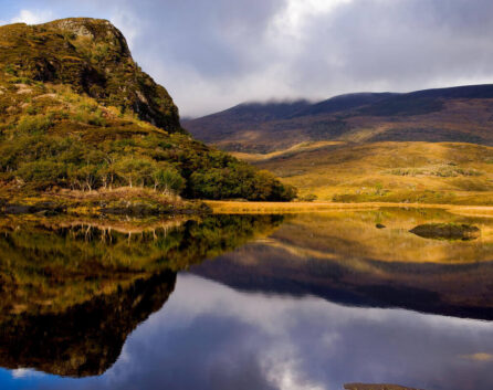 Scenic lake view with lush hills, reflecting tranquil autumn landscape for a peaceful retreat.