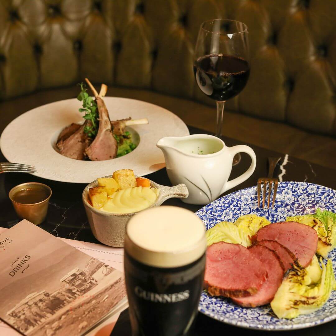 Elegant hotel dining table with gourmet lamb chops, mashed potatoes, wine, menu, creating a luxurious dining experience.