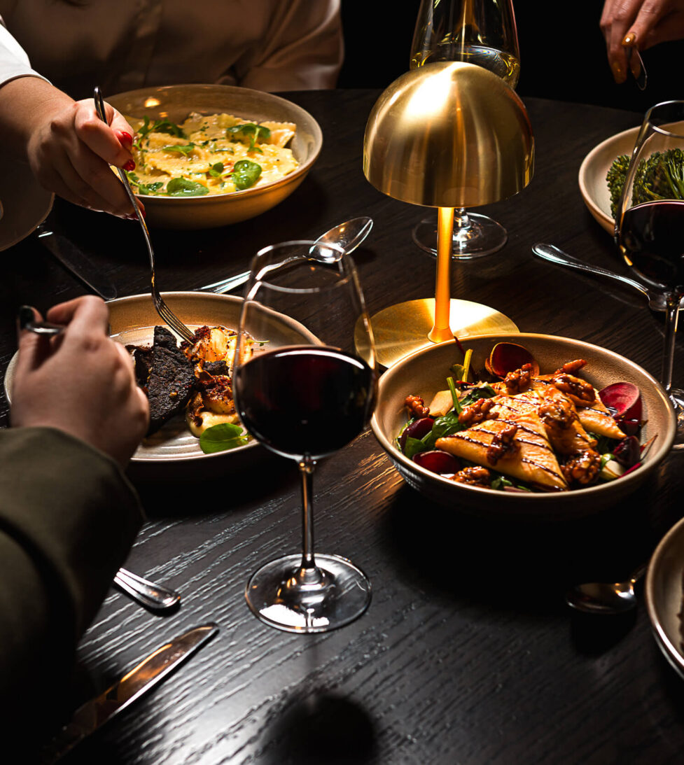 Guests enjoying gourmet dishes and fine wine in an elegant, softly-lit hotel restaurant, perfect for dining experiences.