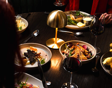 Guests enjoying gourmet dinner and wine at elegant hotel restaurant with ambient lighting.