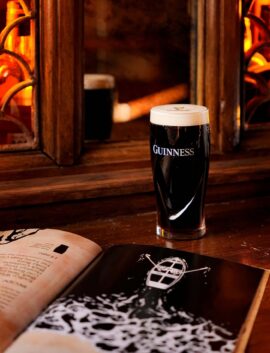 Cosy hotel pub with Guinness pint and warm, amber lighting, offering relaxing atmosphere.