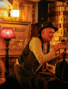 Warm hotel pub with performer holding microphone, rustic decor, wooden walls, whisky sign, and ambient lighting.