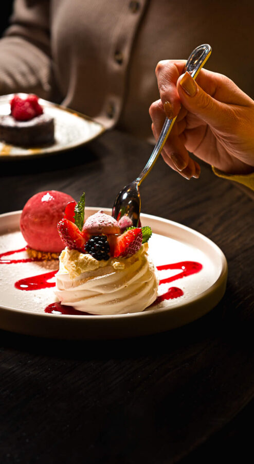 Guests enjoy gourmet desserts and wine in cosy hotel restaurant, featuring elegant plates and vibrant berry toppings.
